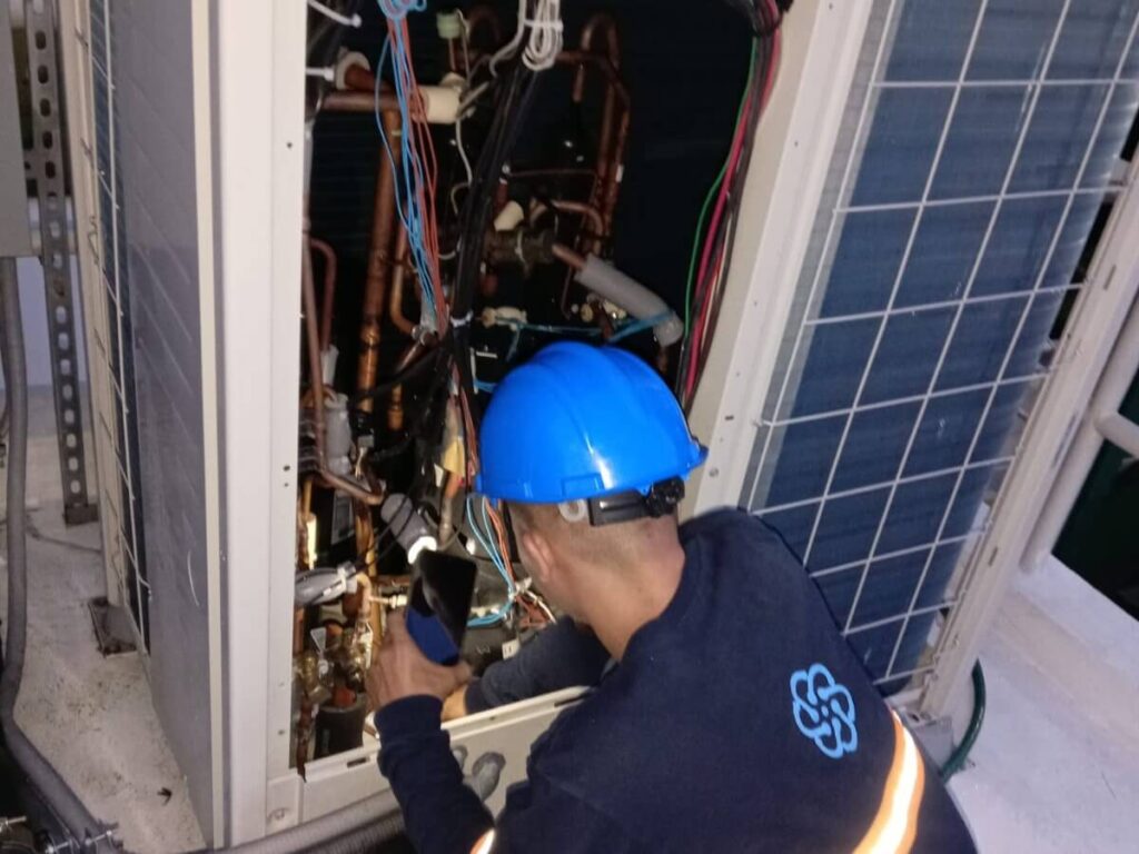 Técnico realizando mantenimiento en unidad HVAC.