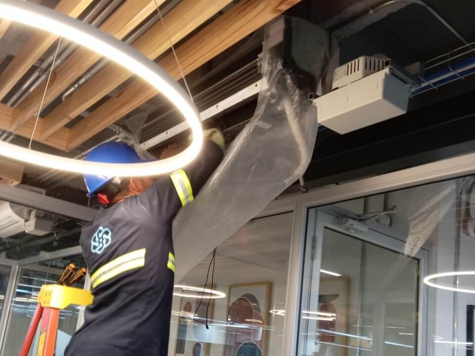Técnico instalando ductos de climatización en interior de edificio.