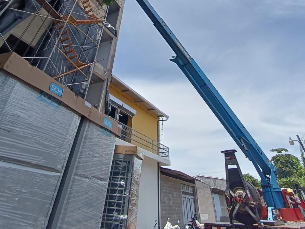 Maniobra con grúa para elevación de equipos HVAC en edificio.