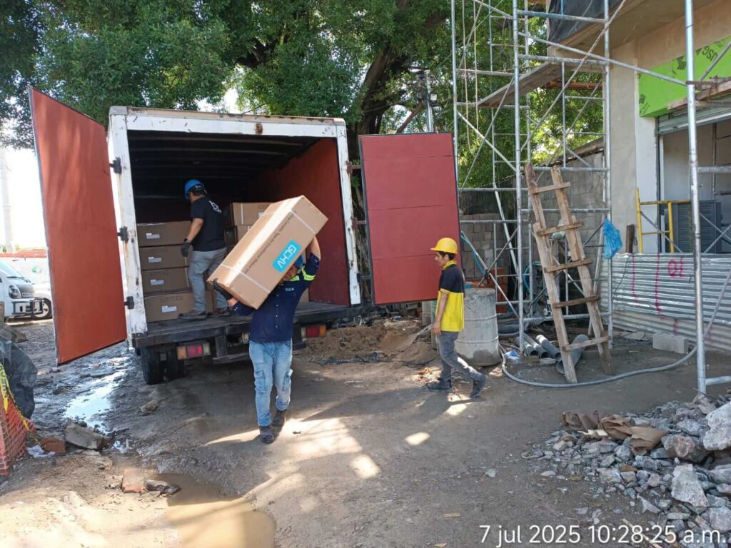 Personal descargando equipos HVAC en obra de construcción.