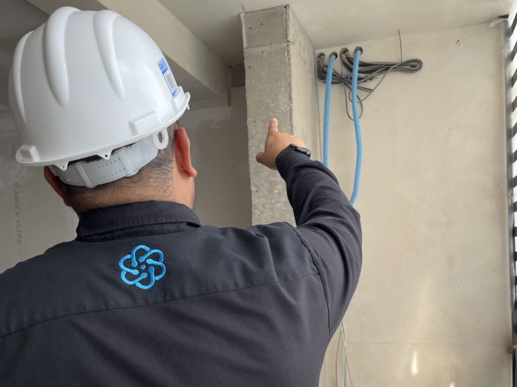 Técnicos instalando sistema de protección eléctrica para aire acondicionado comercial.