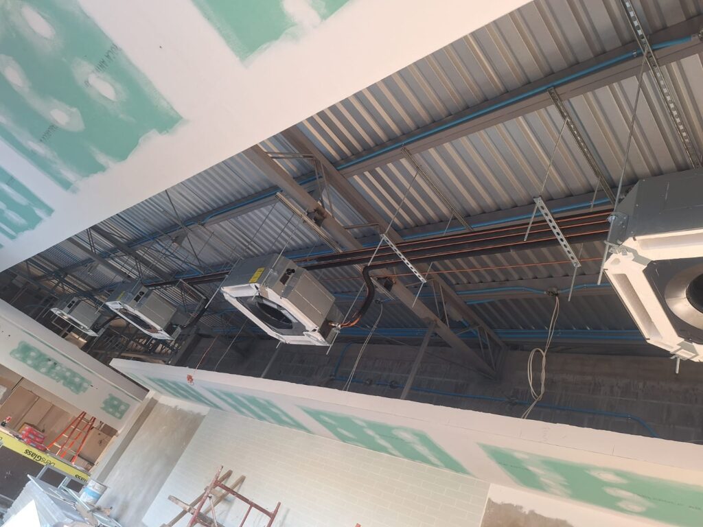 Unidades HVAC tipo cassette suspendidas en estructura metálica durante instalación.